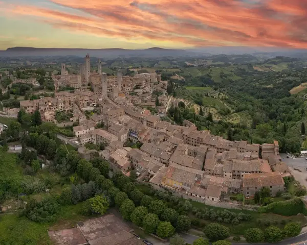 Panoramica aerea di San Gimignano, con le sue torri medievali che svettano tra i tetti rossi. Un sogno di **Volterra e San Gimignano in un giorno**.
