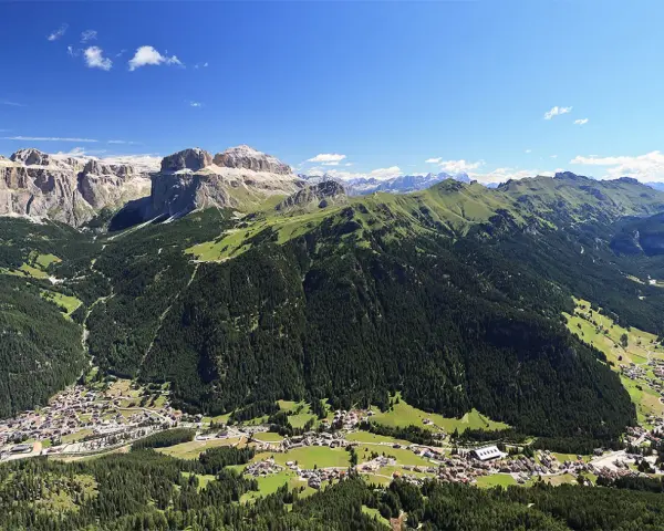 Panoramica delle Dolomiti, ideale per scoprire cosa vedere in Trentino in 3 giorni: valli verdi, boschi fitti e villaggi alpini sotto maestose cime rocciose.