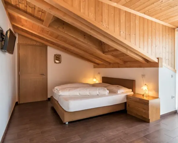 Camera accogliente con tetto in legno e letto matrimoniale. Un'oasi di pace all'hotel Weingarten Kaltern.