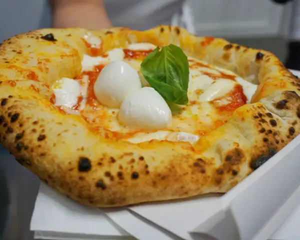 Pizza Margherita appena sfornata, con mozzarella di bufala e basilico fresco. Un vero assaggio di cibo napoletano.