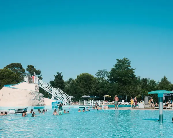 Bambini e adulti si divertono nella piscina del villaggio Ca' Laguna, con scivoli e zone relax sotto il sole.