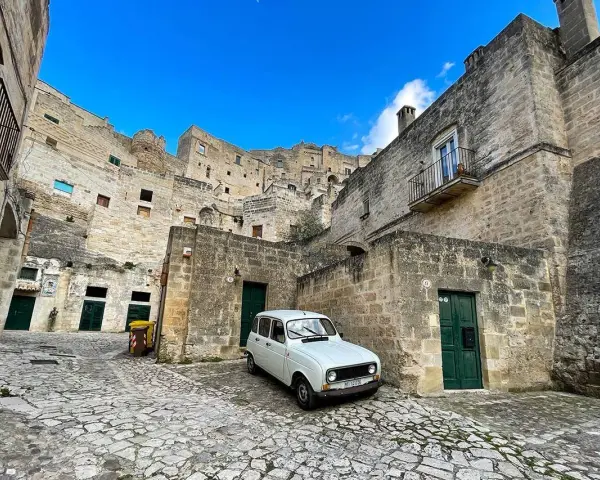 Un'auto d'epoca bianca in un vicolo di Matera, perfetta per visitare la città in un giorno.