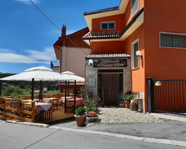 Ristorante La Vecchia Fonte, con tavoli all'aperto sotto ombrelloni bianchi, in una giornata di sole.