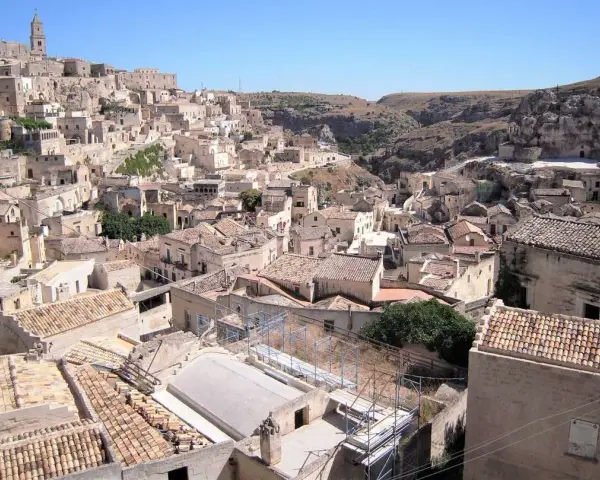 Panoramica dei Sassi di Matera, un **itinerario** suggestivo tra antiche case scavate nella roccia e tetti in cotto sotto un cielo azzurro.