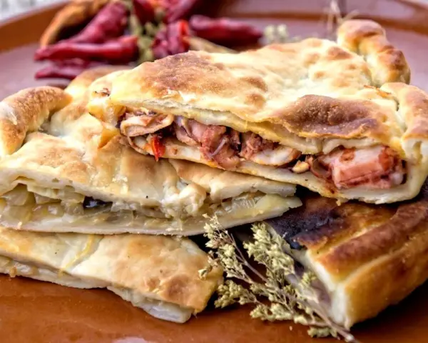 Pasticcio ripieno, un'idea su cosa mangiare a Gaeta. Ripieno di pesce e verdure, con peperoncini secchi sullo sfondo.
