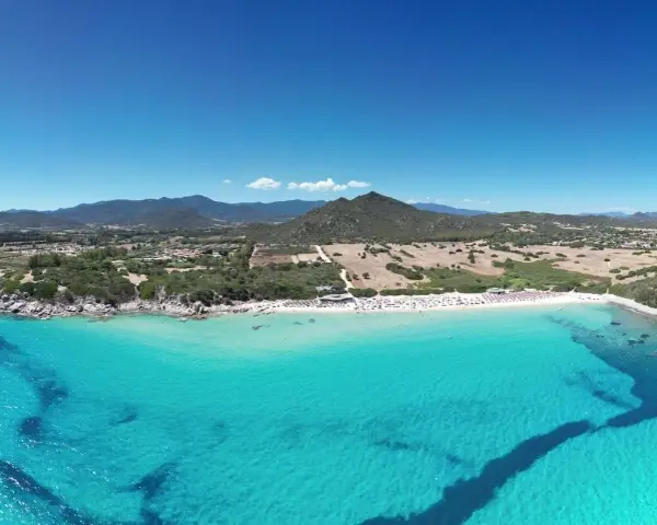 Spiaggia di Castiadas con acque cristalline e montagne sullo sfondo. Un luogo da sogno, quasi come vedere il delfino Castiadas nuotare felice.