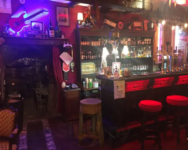 Interno della locanda del Principe a Artena, con chitarra elettrica luminosa, bancone bar e sgabelli rossi.