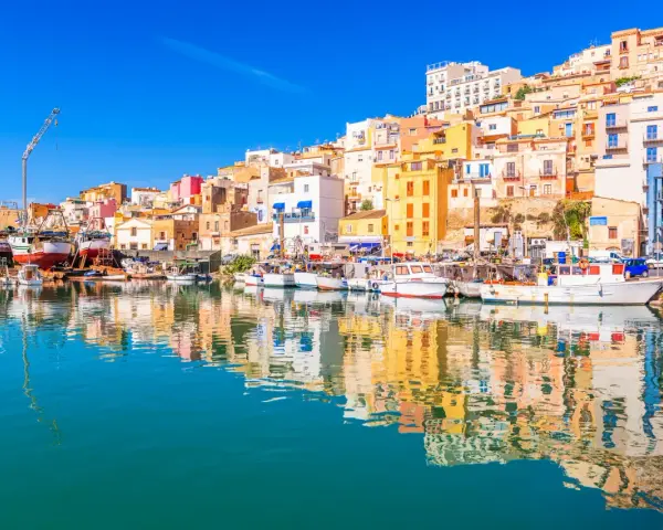 Porto di Sciacca: case colorate a picco sul mare, barche da pesca ormeggiate e riflessi sull'acqua. Un luogo incantevole da scoprire.