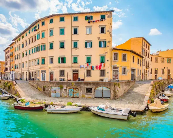 Canali di Livorno, cosa vedere in un giorno: case colorate affacciate sull'acqua, barche ormeggiate e panni stesi al sole.
