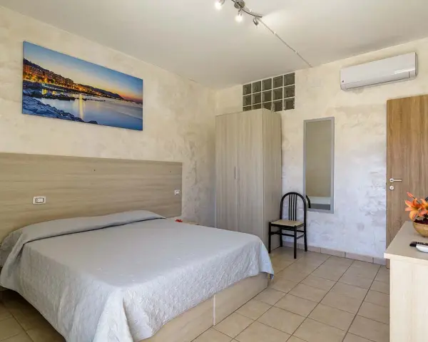 Camera accogliente all'Hotel Cristallo Paestum con letto matrimoniale, armadio, specchio e quadro con panorama marino.