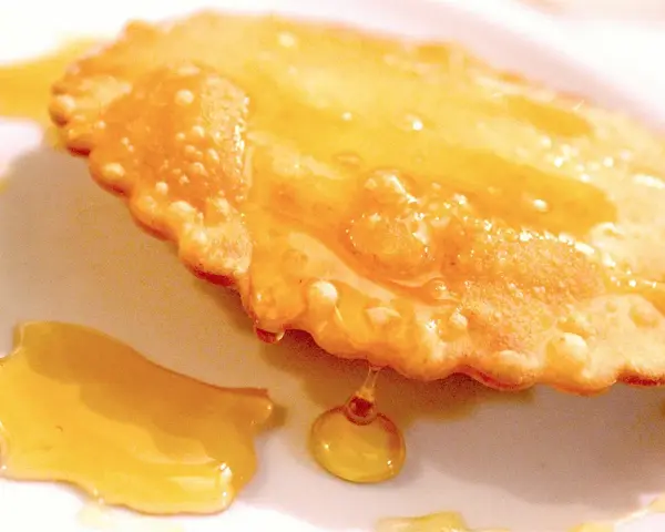Dolce fritto, uno dei 5 piatti tipici della Sardegna, ricoperto di miele dorato.