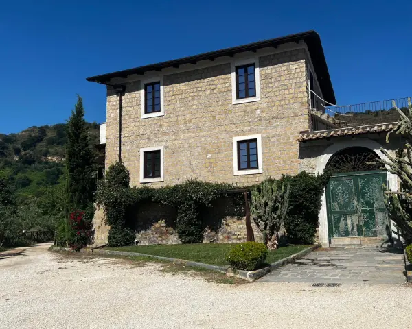 La Masseria del Carmine Maggiore, con le sue mura in pietra chiara e il verde rigoglioso, incanta sotto un cielo azzurro.