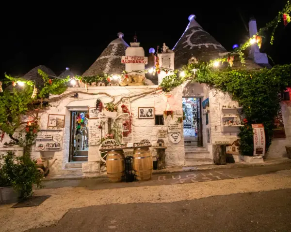 Trulli illuminati di notte ad Alberobello, con luci e decorazioni. Un invito a scoprire le cose da fare a Alberobello, tra negozi e prodotti tipici.