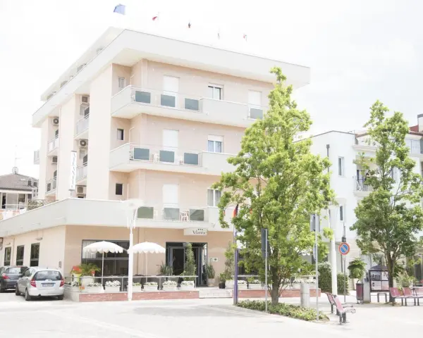 Hotel Atlantic Igea Marina: scopri i prezzi per la tua vacanza al mare. Edificio moderno con alberi verdi davanti.