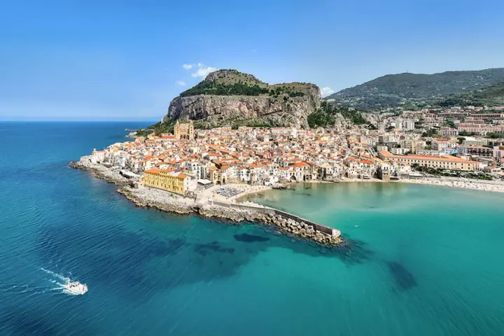 Vista aerea di Cefalù, con le sue spiagge siciliane orientali, il borgo arroccato e il mare cristallino.