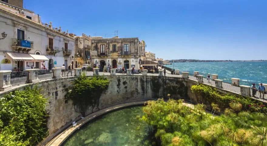 Passeggiata sul lungomare di Ortigia, Siracusa, ideale per un tour sicilia sud orientale 7 giorni. L'acqua cristallina e i papiri incantano.