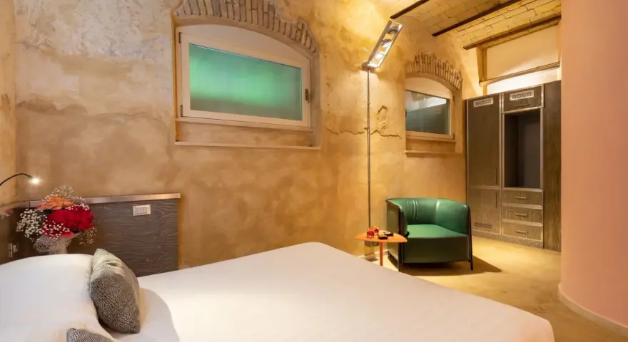 Camera accogliente con letto, poltrona verde e armadio. Un tocco di lusso, come un boscolo circo massimo, per un soggiorno indimenticabile.
