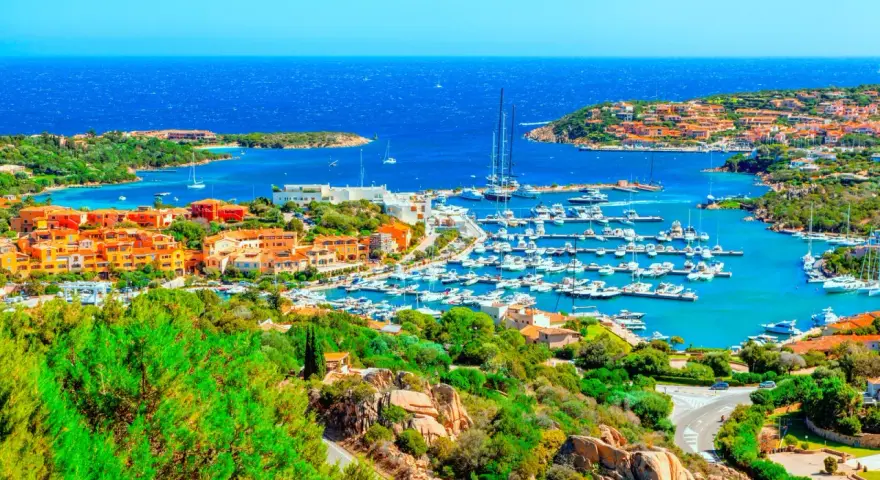 Vista panoramica di Porto Cervo con il suo porto turistico pieno di yacht e le case colorate che si affacciano sul mare cristallino. Un luogo da sogno per scoprire cosa vedere a Porto Cervo.