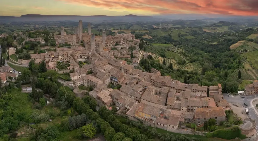 Panoramica aerea di San Gimignano, con le sue torri medievali che svettano tra i tetti rossi. Un sogno di **Volterra e San Gimignano in un giorno**.