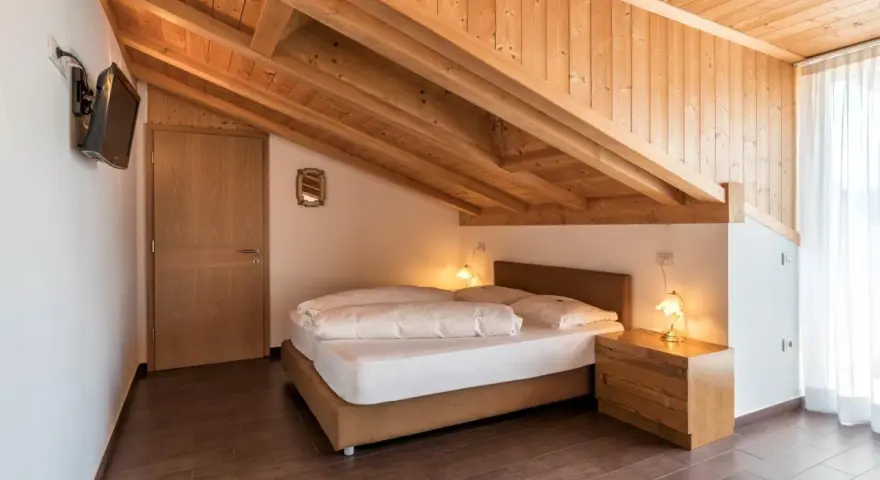 Camera accogliente con tetto in legno e letto matrimoniale. Un'oasi di pace all'hotel Weingarten Kaltern.