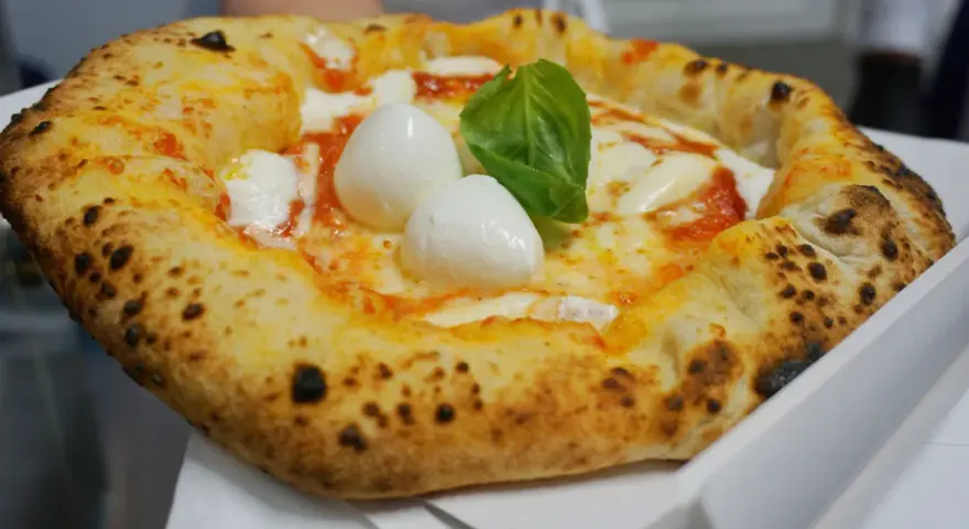 Pizza Margherita appena sfornata, con mozzarella di bufala e basilico fresco. Un vero assaggio di cibo napoletano.