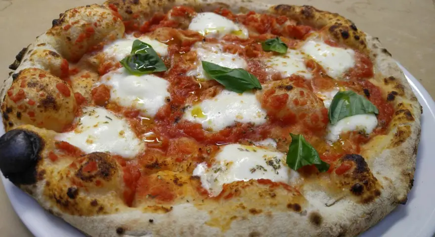 Pizza margherita con mozzarella filante, pomodoro e basilico fresco. Una vera casa matta, nota per la sua bontà.