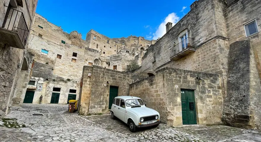 Un'auto d'epoca bianca in un vicolo di Matera, perfetta per visitare la città in un giorno.