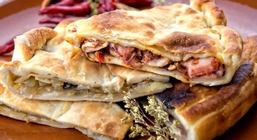 Pasticcio ripieno, un'idea su cosa mangiare a Gaeta. Ripieno di pesce e verdure, con peperoncini secchi sullo sfondo.