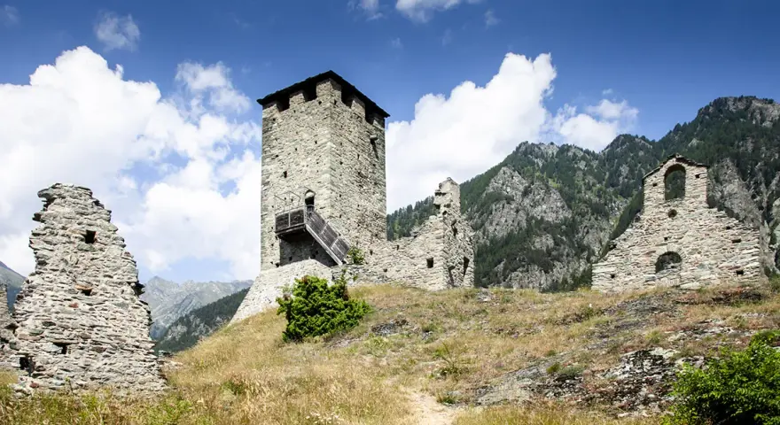 Rovine di un castello con torre in pietra, un invito a visitare la Valle d'Aosta.