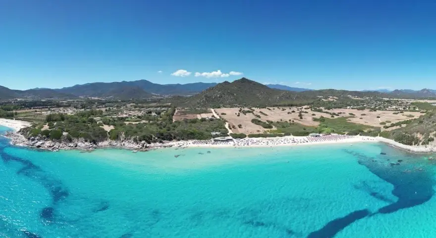 Spiaggia di Castiadas con acque cristalline e montagne sullo sfondo. Un luogo da sogno, quasi come vedere il delfino Castiadas nuotare felice.