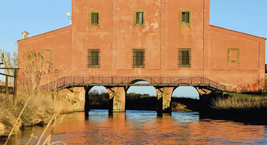 Antico edificio con ponte ad archi su un canale, un luogo suggestivo da scoprire a Castiglione della Pescaia.