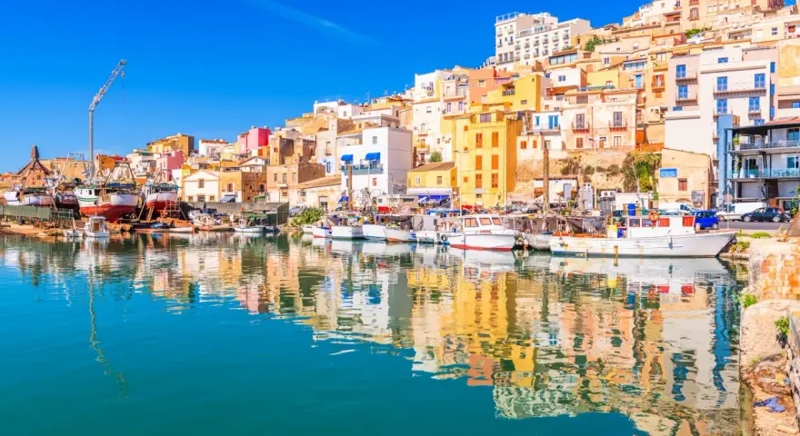Porto di Sciacca: case colorate a picco sul mare, barche da pesca ormeggiate e riflessi sull'acqua. Un luogo incantevole da scoprire.