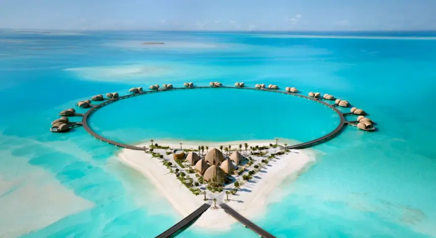 Resort circolare su un'isola tropicale, perfetto per le tue vacanze ad agosto. Case sull'acqua e sabbia bianca.