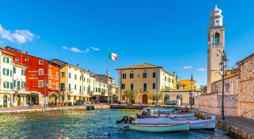 Lazise: cosa vedere nel borgo sul lago. Case colorate, porto con barche e campanile.