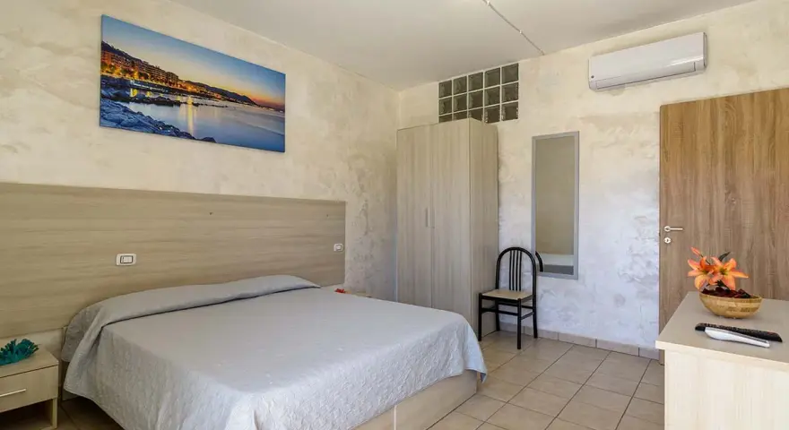 Camera accogliente all'Hotel Cristallo Paestum con letto matrimoniale, armadio, specchio e quadro con panorama marino.