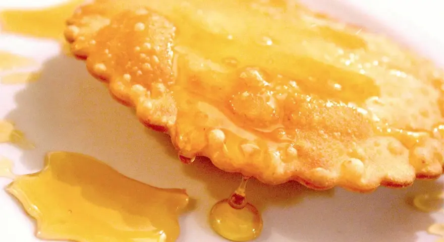 Dolce fritto, uno dei 5 piatti tipici della Sardegna, ricoperto di miele dorato.