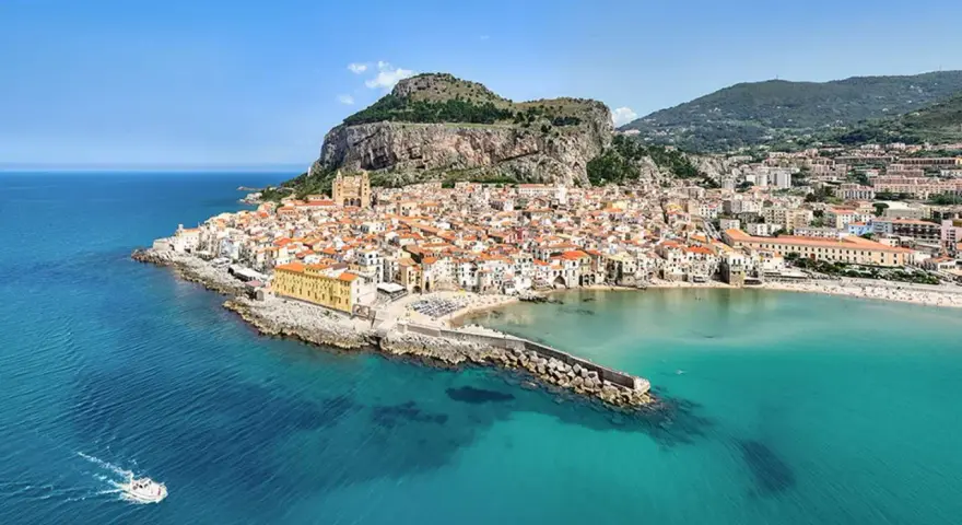 Vista aerea di Cefalù, con le sue spiagge siciliane orientali, il borgo arroccato e il mare cristallino.
