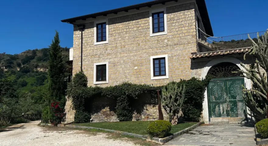 La Masseria del Carmine Maggiore, con le sue mura in pietra chiara e il verde rigoglioso, incanta sotto un cielo azzurro.