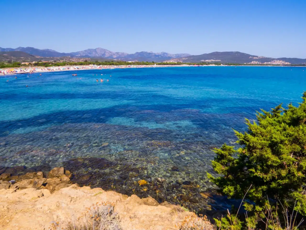 La spiaggia di Budoni, con acque cristalline e montagne sullo sfondo, &egrave; un paradiso per chi ama il mare.