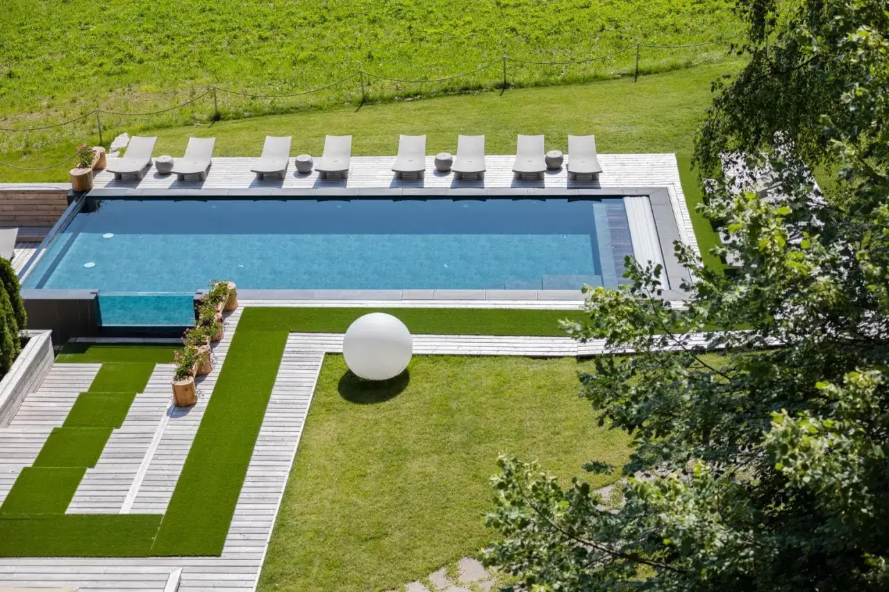 Piscina a sfioro e lettini prendisole con vista sui prati verdi, un'oasi di relax al Linta Hotel Asiago.