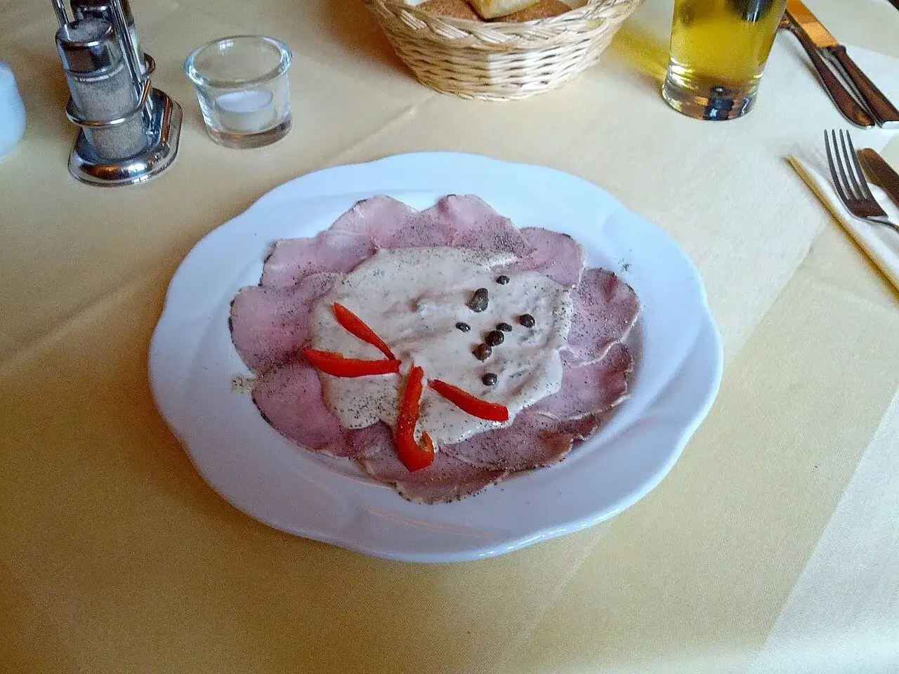 Vitello tonnato, un classico del cibo tipico Torino, servito su un piatto bianco con salsa cremosa, capperi e peperoncino.
