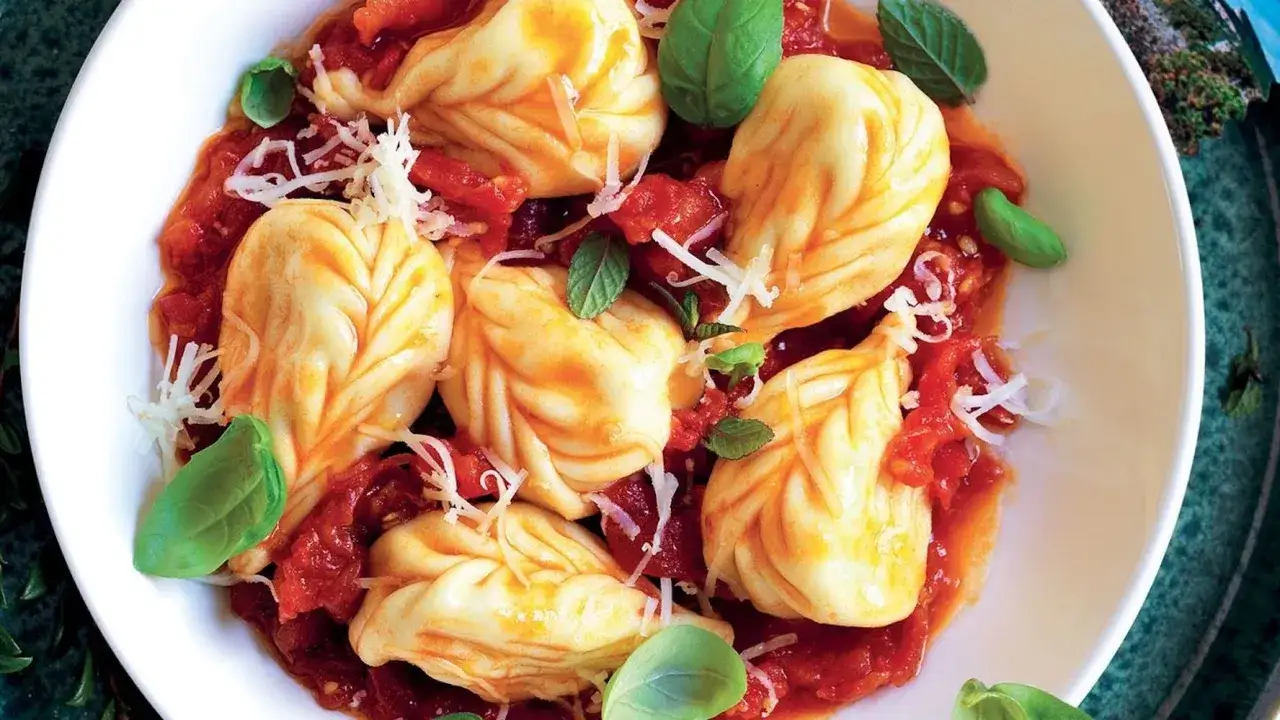 Un piatto di culurgiones, uno dei 5 piatti tipici della Sardegna, conditi con sugo di pomodoro, basilico e pecorino grattugiato.