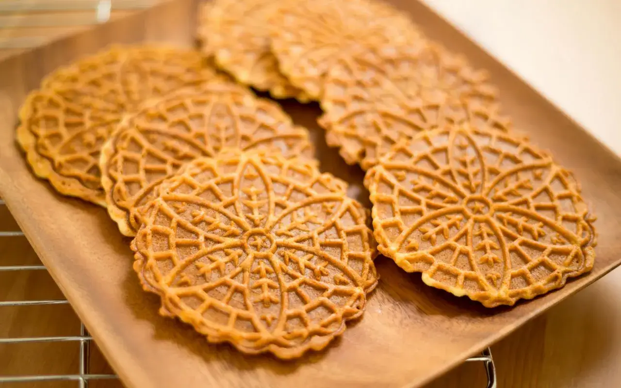 Pizzelle, dolci tipici della gastronomia abruzzese, su un piatto di legno.