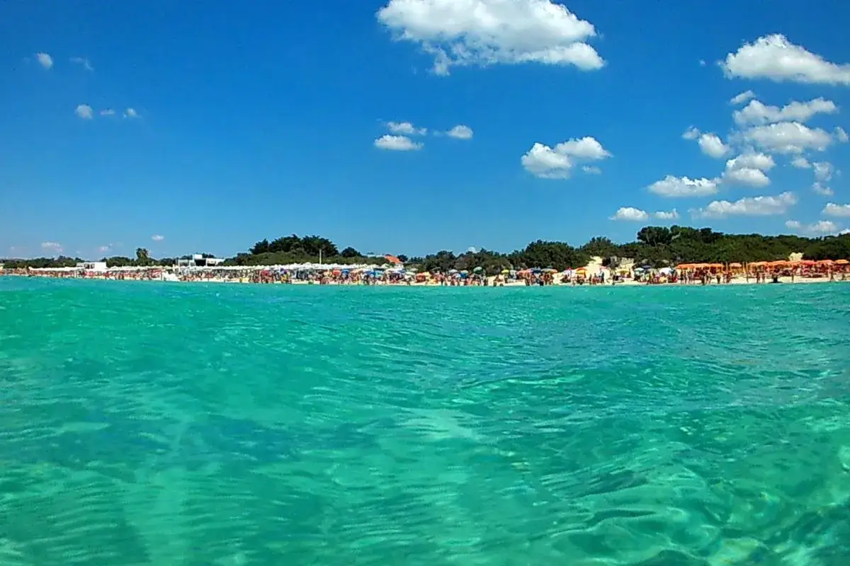 Acque cristalline e spiagge affollate a Porto Cesareo, tra le più belle del Salento. Ombrelloni colorati e gente che si gode il sole.