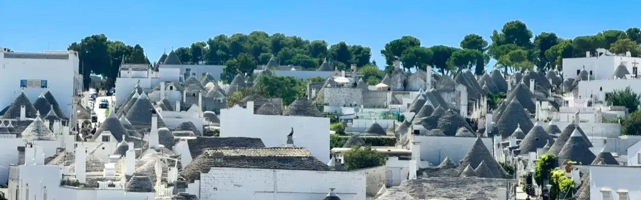 Panoramica della Valle d'Itria con i suoi iconici trulli. Un paesaggio unico da esplorare, tra tetti conici e case bianche.