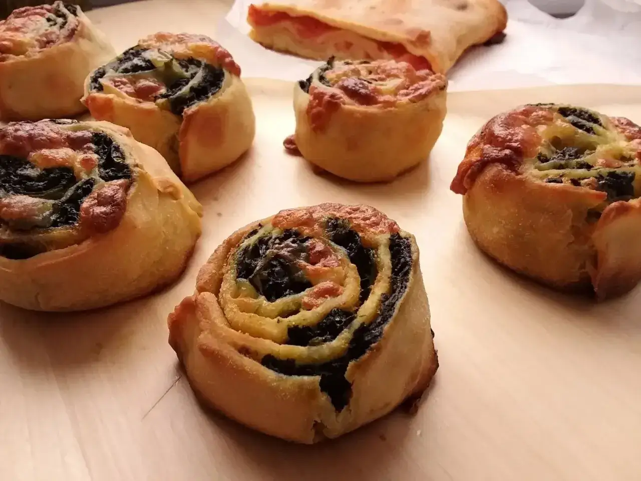 Rotolini di pasta sfoglia con spinaci e formaggio, un assaggio dei piatti tipici ragusani. Sullo sfondo, una fetta di focaccia al pomodoro.