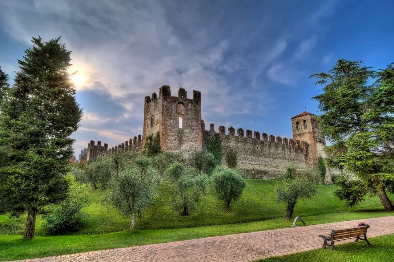 Le mura del castello di Lazise cosa vedere, con ulivi e un sentiero in mattoni.
