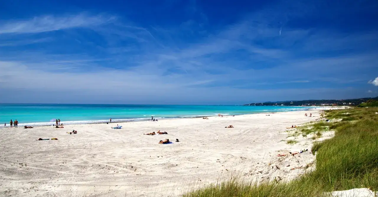 Spiaggia di Vada Village, con sabbia bianca, mare turchese e persone che prendono il sole. Le recensioni confermano la bellezza del posto.