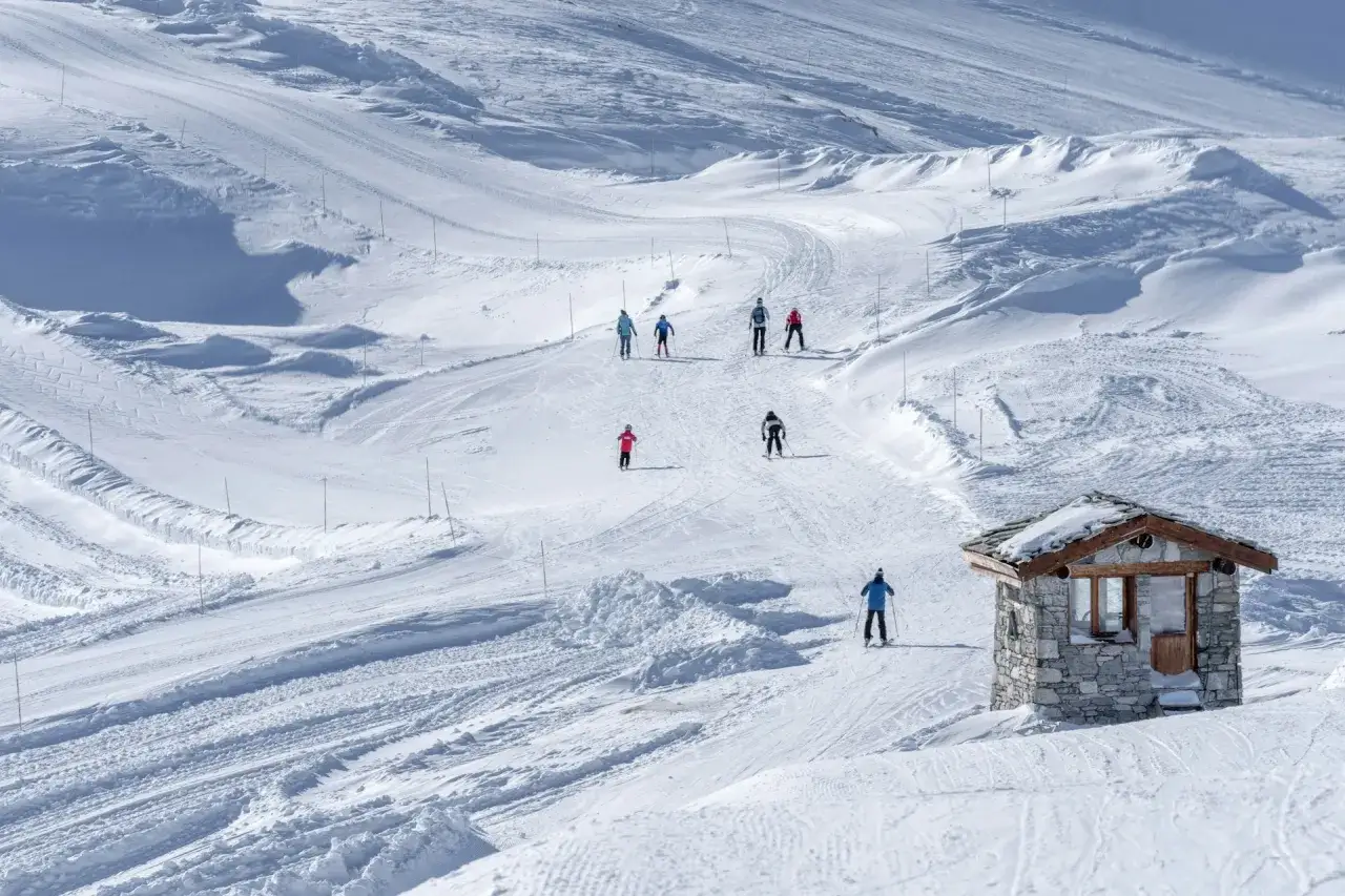 Piste innevate, sciatori in discesa e un piccolo rifugio in pietra: l'ideale per la tua settimana bianca dove andare.