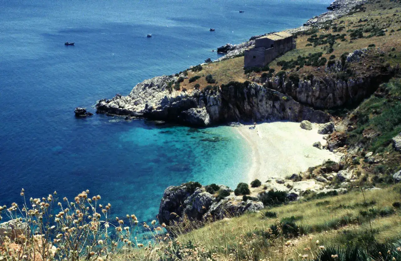 Una baia incantevole, tra le spiagge più belle in Sicilia, con acque cristalline e un'antica costruzione sulla scogliera.